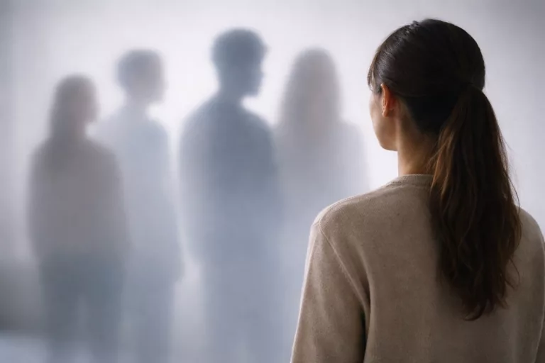 Frau steht vor verschwommenen Personen.