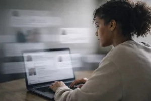 Junge Frau sitzt am Schreibtisch und schaut auf den Laptop mit Social Media Inhalten Content Marketing funktioniert nicht Warum Content nicht funktioniert (auch wenn er gut ist) Textagentur Textineers
